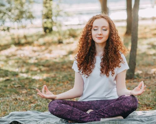 Person meditating peacefully in a serene natural environment.